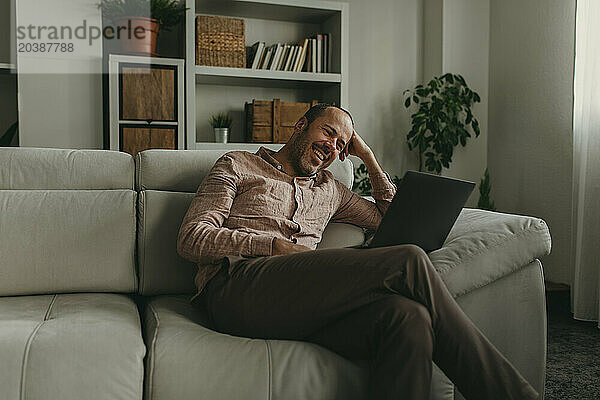 Smiling man watching movie on laptop at home