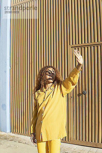 Young woman in yellow casuals shielding eyes with hand on sunny day