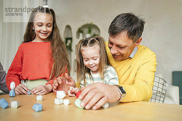 Grandfather playing game with granddaughters at home