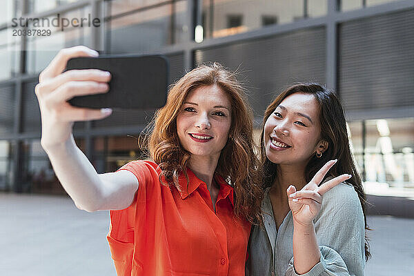 Woman taking selfie with friend making peace sign