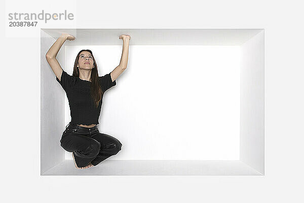 Teenager touching alcove squatting against white background