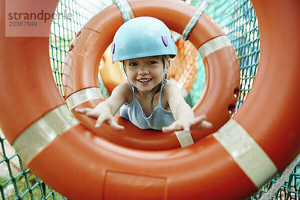 Smiling girl wearing helmet and doing obstacle course at rope park