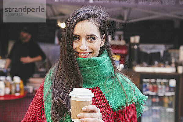 Happy woman with disposable coffee cup at coffee shop