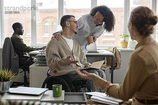 Happy business people congratulating colleague with disability for getting promotion in office