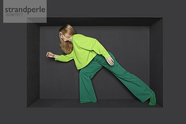 Blond teenage girl standing in alcove over black background