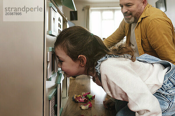 Smiling father and daughter playing with dollhouse