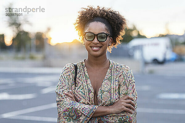 Smiling woman with arms crossed at parking lot