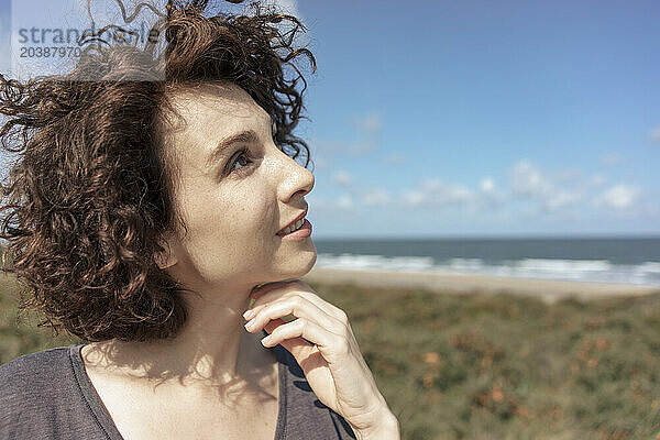 Thoughtful woman smiling at beach on sunny day