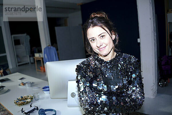 Smiling beautiful businesswoman wearing sequin dress at home office