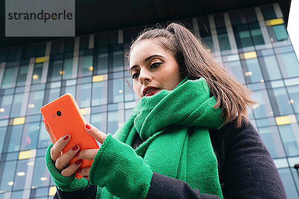 Beautiful woman using smart phone in front of building