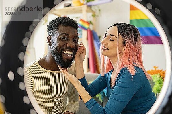 Happy non-binary person getting dressed by friend at home