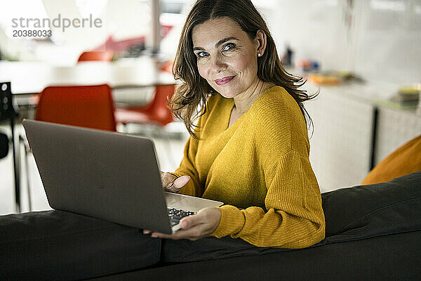 Smiling manager using laptop in creative office
