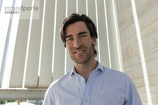 Confident young businessman in front of wall