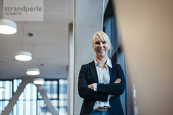 Happy businesswoman standing with arms crossed