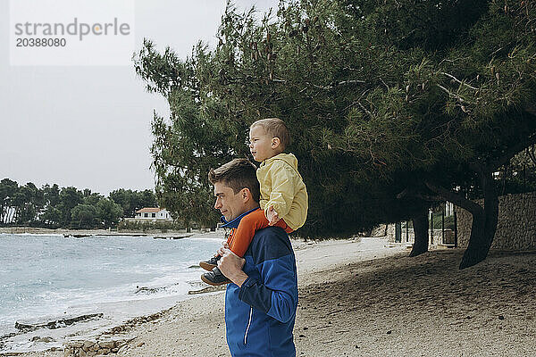 Father carrying son on shoulders at beach