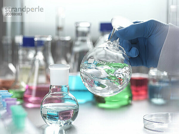 Hand of senior scientist stirring chemical in flask at laboratory