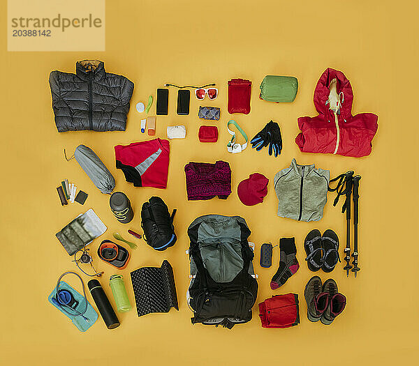 Travel kit for hiking organized against yellow background