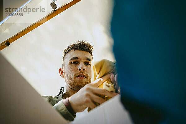 Low angle view of male volunteer removing clothes from box during charity drive at community center