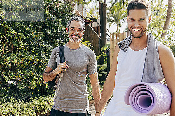 Portrait of happy multiracial male friends in sports clothing standing at wellness resort