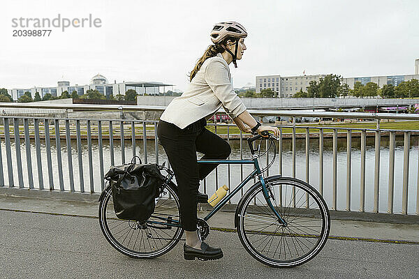 Side view of businesswoman cycling on promenade in city