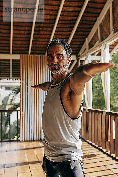 Determined man doing Warrior 2 pose at wellness resort