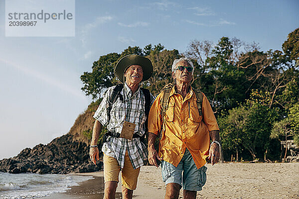 Senior gay couple walking together at beach on vacation