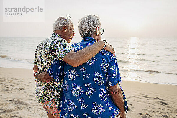 Gay couple with arms around at beach on vacation