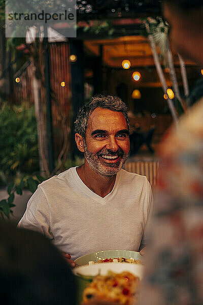 Happy mature man during dinner at restaurant on vacation