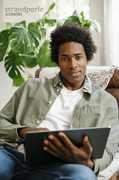 Confident businessman using laptop reclining on lounge chair working at home