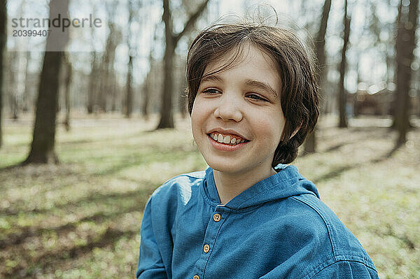 Happy boy in front of trees at park