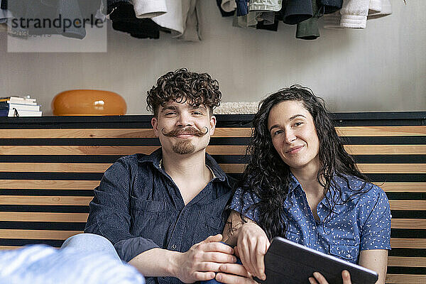 Smiling woman holding tablet PC sitting with boyfriend at home