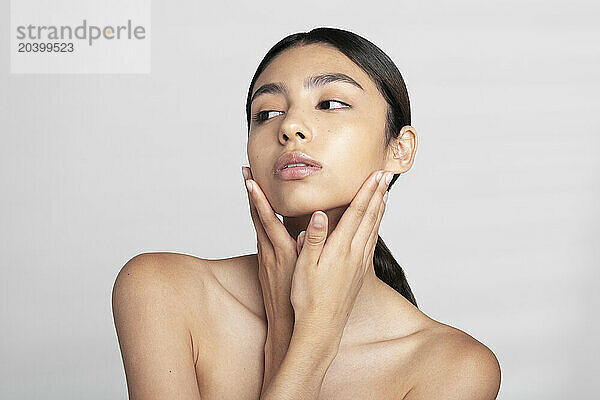 Beautiful young woman looking away against white background