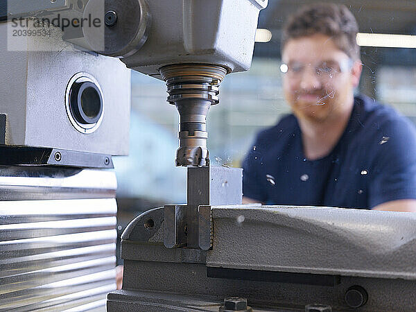 Engineer operating drill through CNC machine at factory