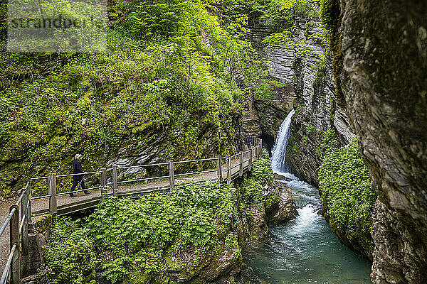 Senior woman hiking on footpath by Thur waterfall in forest