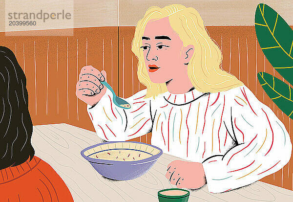 Blond woman eating soup and talking with friend at table