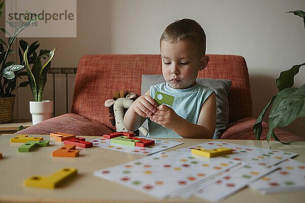 Boy solving puzzle game on table at home