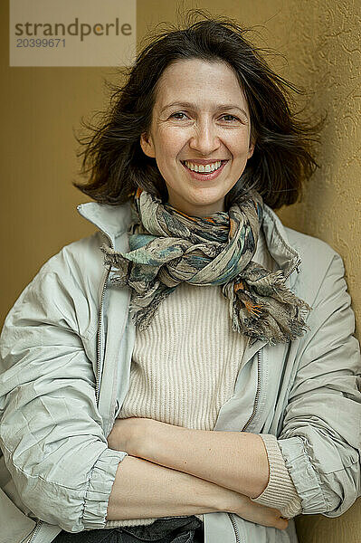 Smiling woman with arms crossed leaning on wall