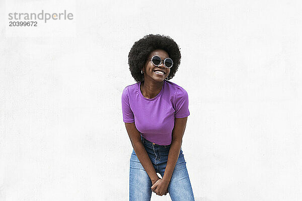 Happy young Afro woman standing against white background