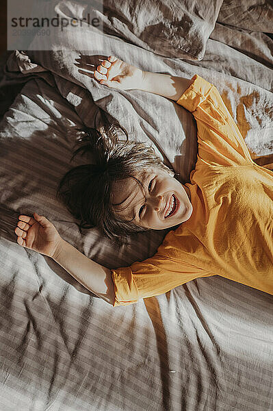 Cheerful boy lying on bed in bedroom at home