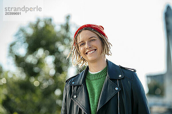 Smiling young woman wearing knit hat and leather jacket