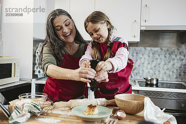 Happy grandmother and granddaughter preparing food together in kitchen at home