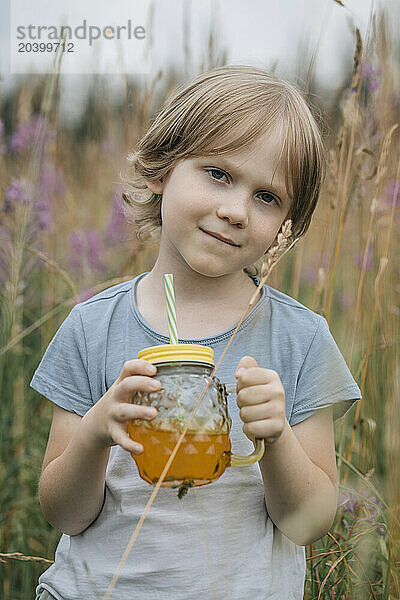 Boy standing with mason jar in field