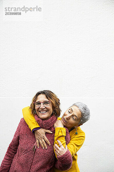 Happy lesbian couple enjoying near white wall