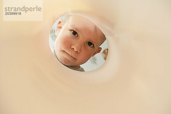 Curious boy looking through paper tube