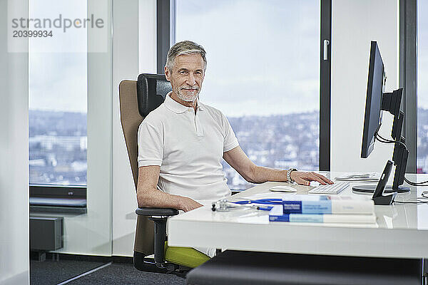 Portrait of confident doctor sitting at desk in medical practice