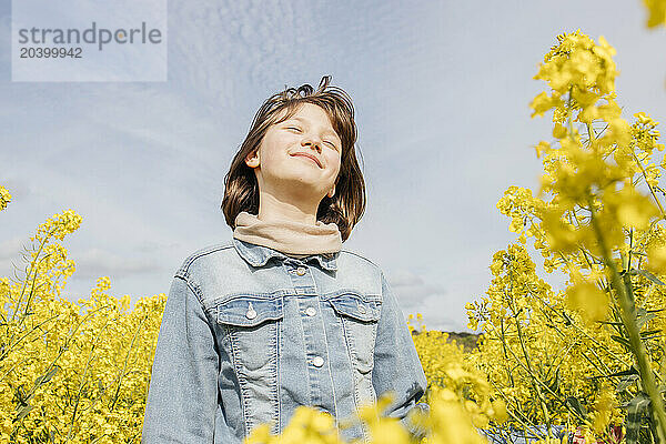 Smiling girl with eyes closed in rapeseed field