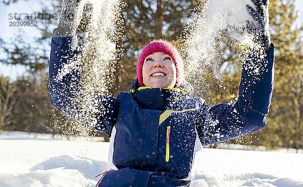 Happy woman throwing snow in winter