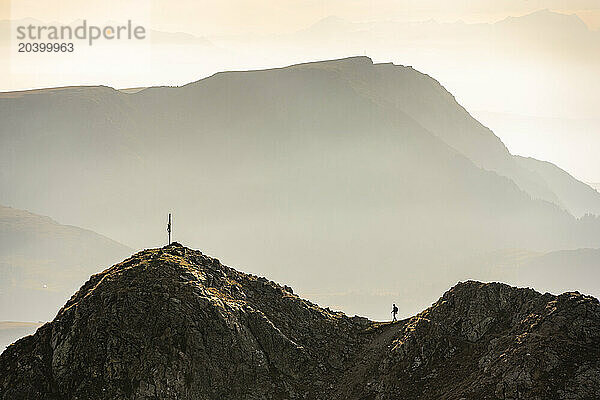 Italy  South Tyrol  Silhouette of hiker walking toward Samspitze summit cross