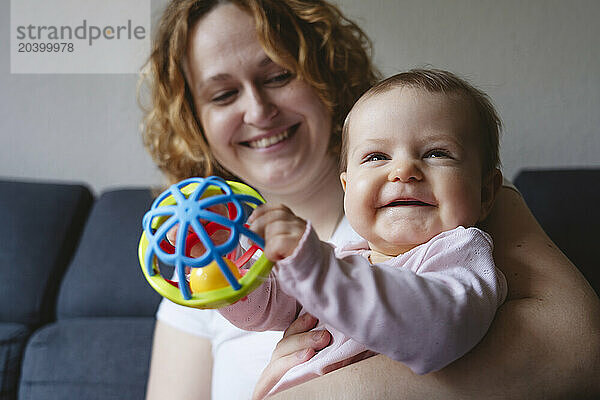 Smiling woman with daughter playing with toy at home