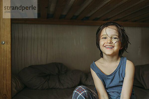 Smiling boy sitting on bed at home